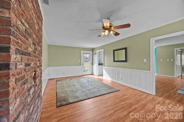 a view of an empty room with wooden floor and a chandelier