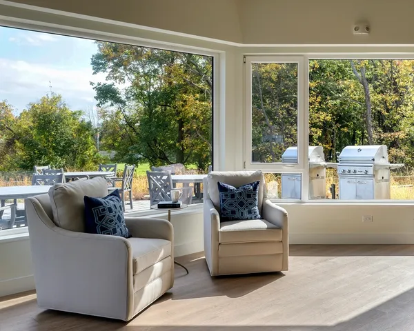 a living room with couches chairs and a floor to ceiling window with pool view