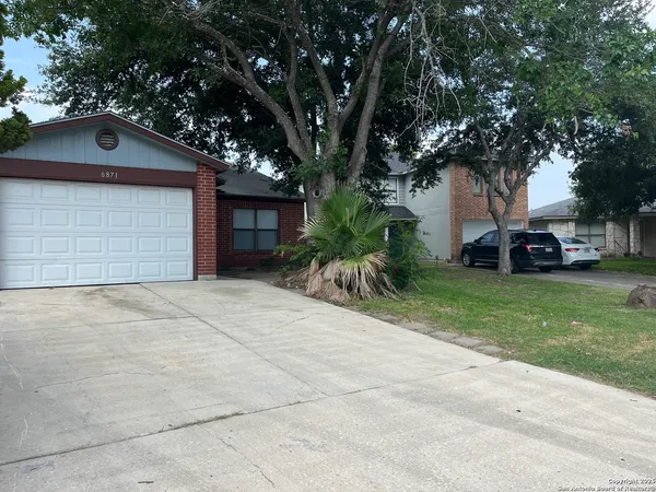 a front view of a house with a garden and trees