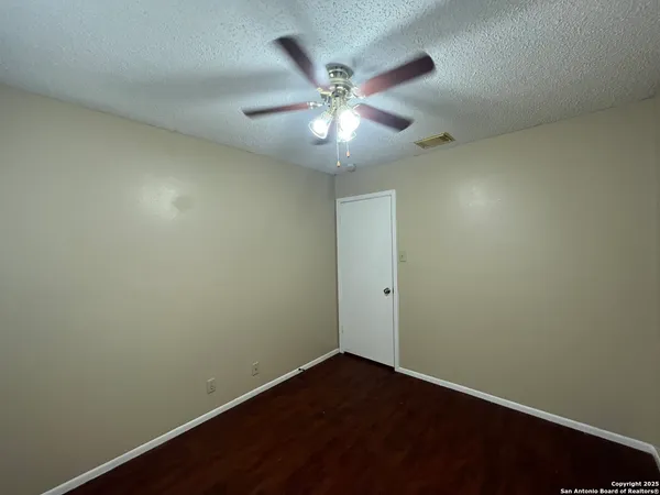 an empty room with a ceiling fan and wooden floor