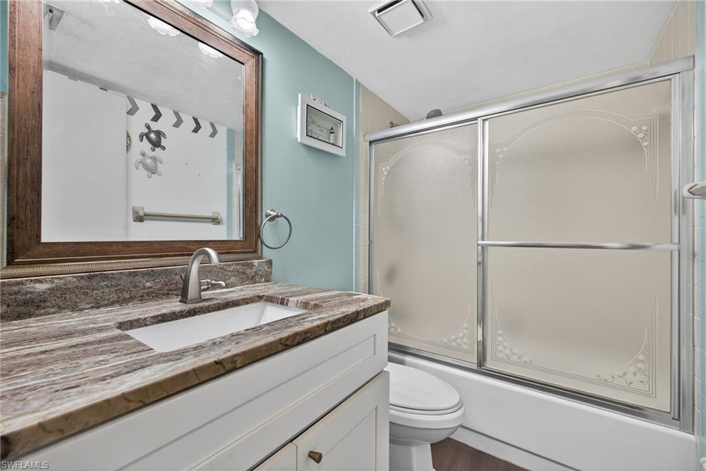 1223 Commonwealth Circle, Unit F201 Naples, FL 34116 - Photo 22 of 25 a bathroom with a granite countertop sink a toilet a shower and a mirror