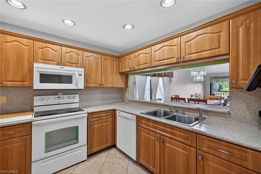 1223 Commonwealth Circle, Unit F201 Naples, FL 34116 - Photo 4 of 25 a kitchen with granite countertop a sink stainless steel appliances and cabinets