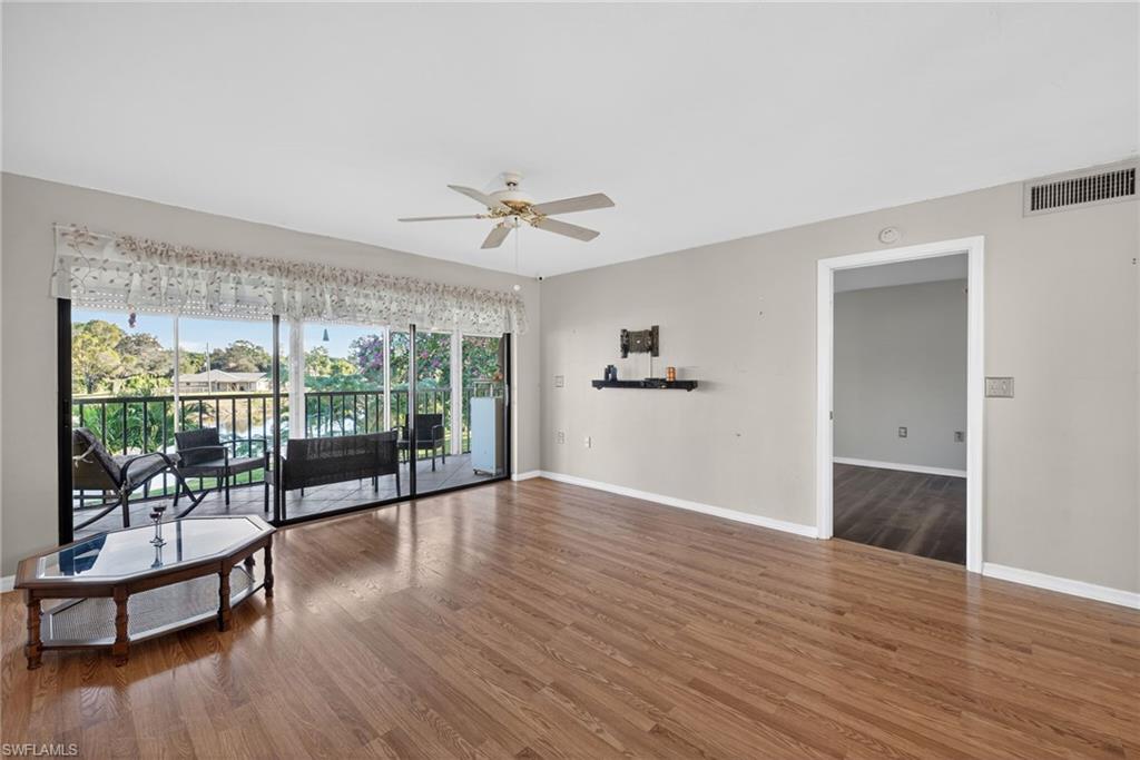 1223 Commonwealth Circle, Unit F201 Naples, FL 34116 - Photo 9 of 25 a view of a livingroom with wooden floor and a ceiling fan