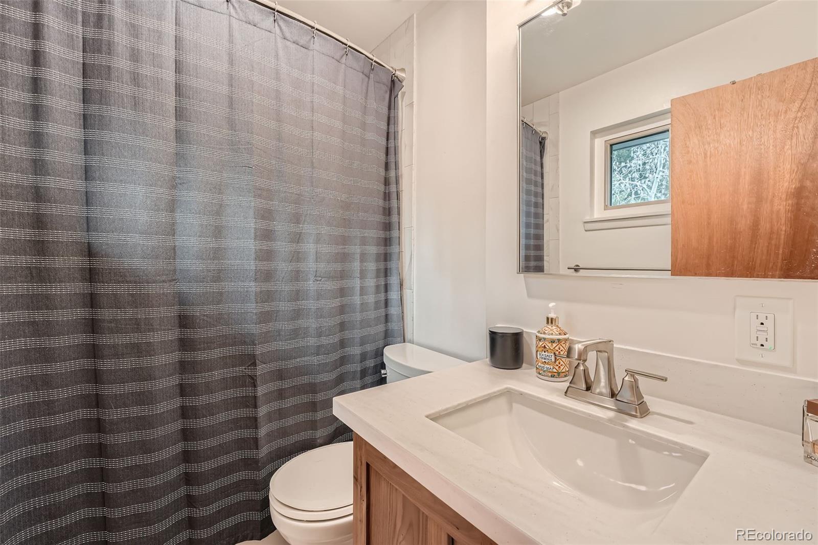 28669 Mountain View Road Conifer, CO 80433 - Photo 14 of 40 a bathroom with a sink a toilet and shower curtain