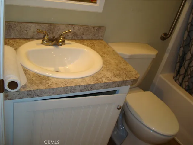 a bathroom with a granite countertop toilet and a sink