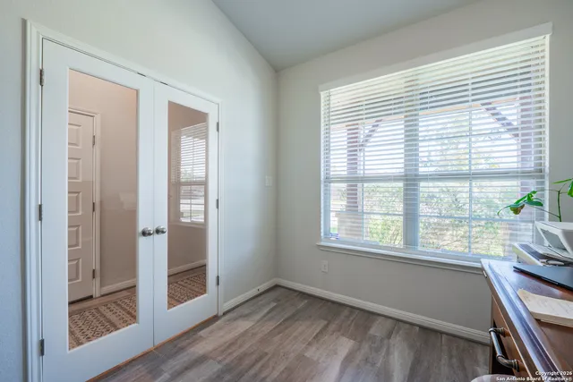 a view of an empty room with wooden floor and a window