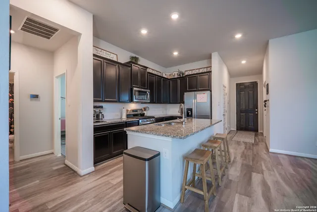 a large kitchen with stainless steel appliances granite countertop a stove refrigerator and a wooden floor