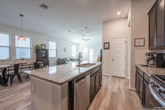 a kitchen with granite countertop kitchen island stainless steel appliances a sink stove and refrigerator