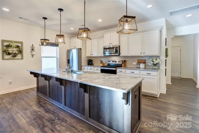 a kitchen with kitchen island a counter space a sink appliances and cabinets
