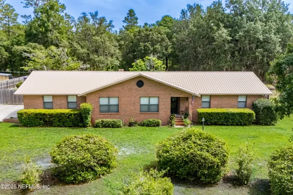 a aerial view of a house next to a big yard and large trees