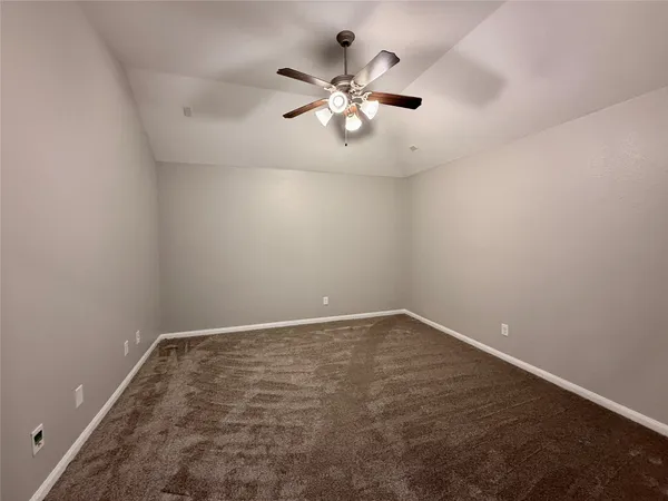 an empty room with chandelier fan and windows