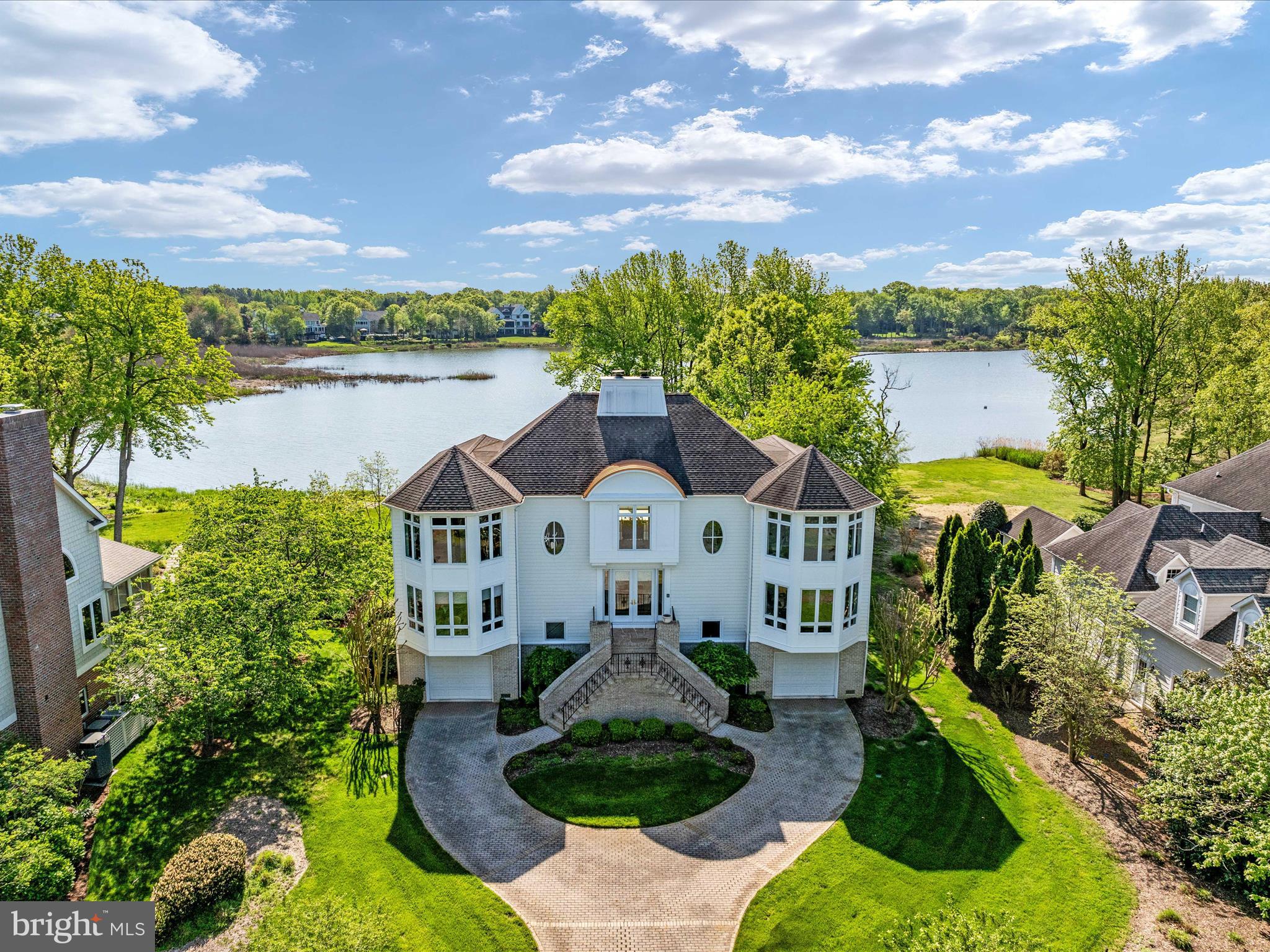 a front view of a house with a garden and lake view
