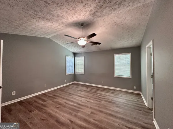 a view of an empty room with window and wooden floor