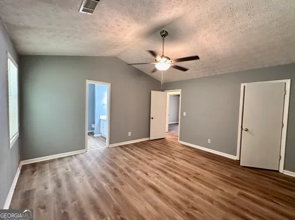 a view of an empty room with a chandelier fan and wooden floor