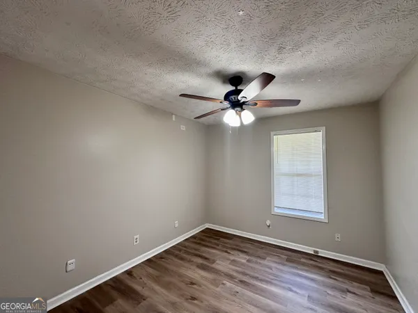 an empty room with wooden floor fan and windows