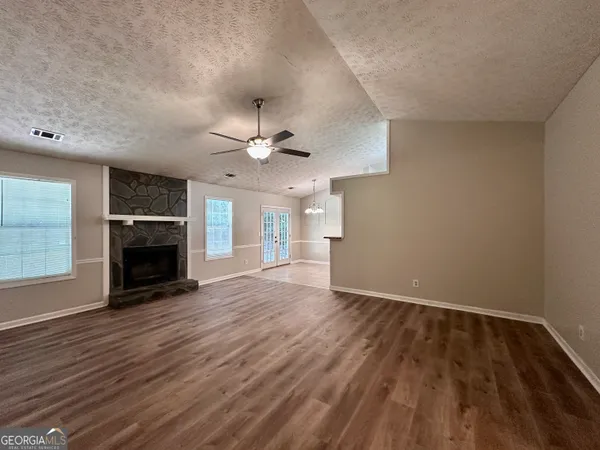 an empty room with wooden floor fireplace and chandelier