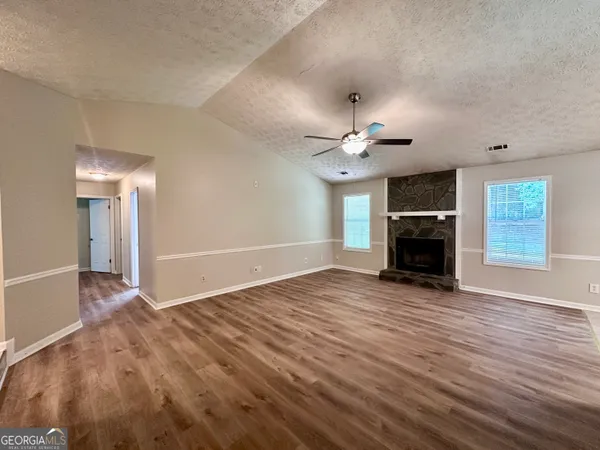 an empty room with wooden floor fireplace and windows