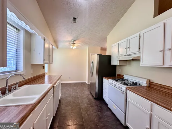 a kitchen with granite countertop a sink stove and refrigerator