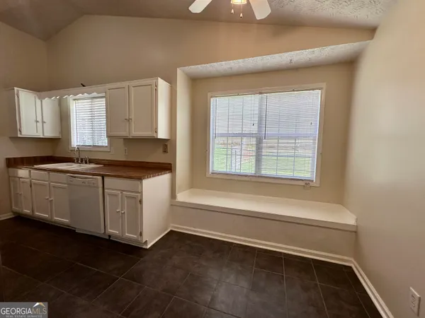 a kitchen with granite countertop white cabinets and white appliances