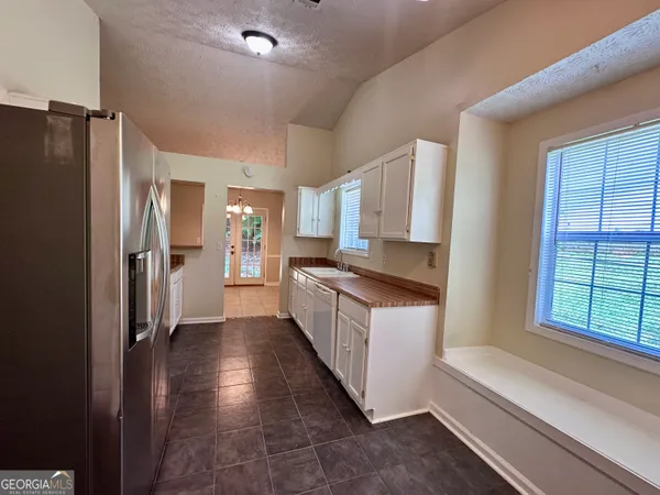 a large kitchen with a refrigerator a sink and dishwasher a oven a large window