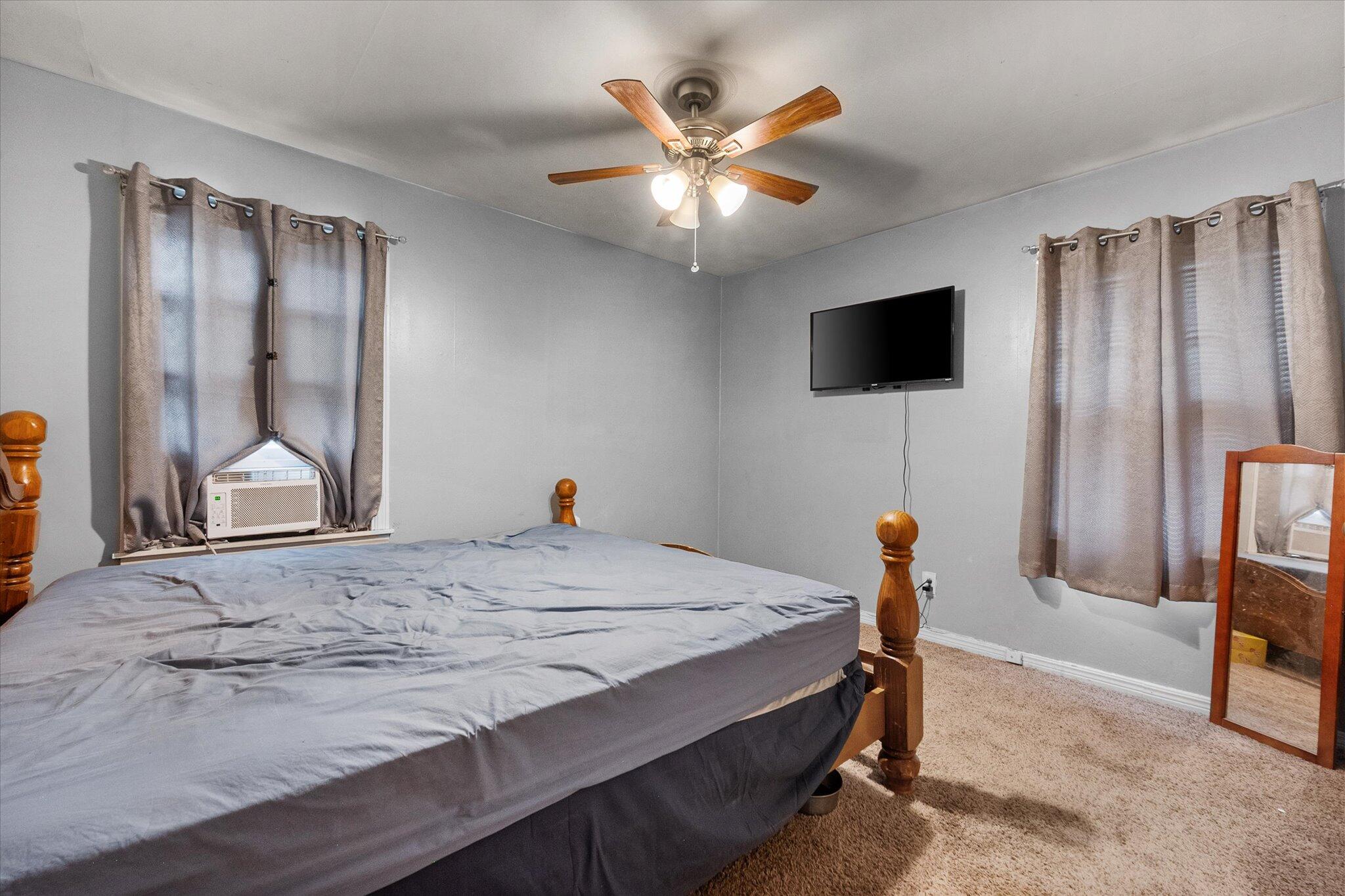 2013 58th Street Lubbock, TX 79412 - Photo 11 of 17 a bedroom with a bed and a flat screen tv
