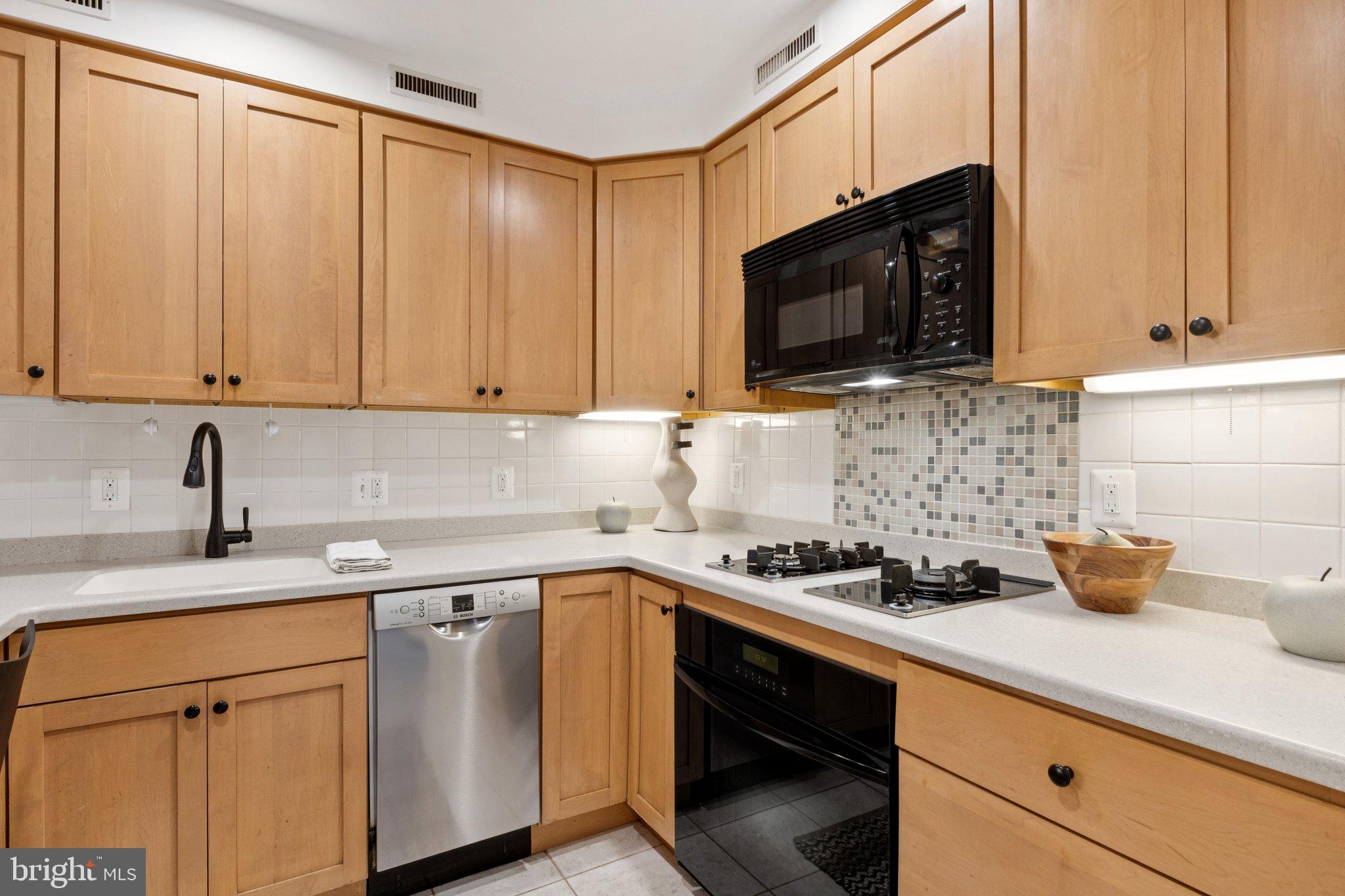 1880 Columbia Road Northwest, Unit 204 Washington, DC 20009 - Photo 5 of 23 a kitchen with stainless steel appliances granite countertop a sink a stove a microwave oven with cabinets and wooden floor
