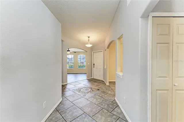 a view of an empty room with kitchen and window