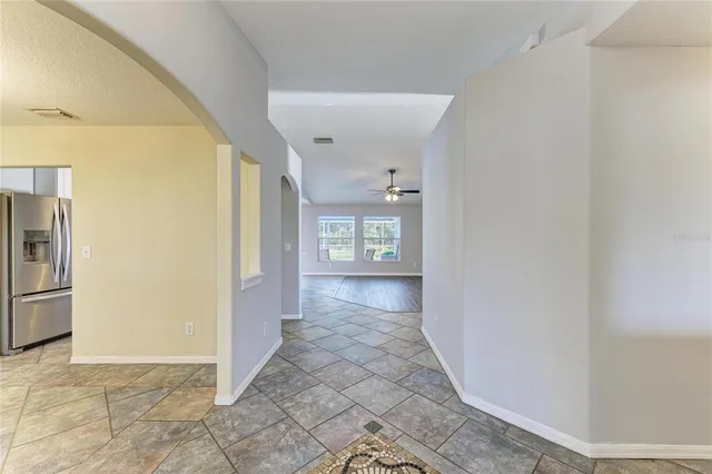 a view of an empty room with wooden floor and a kitchen