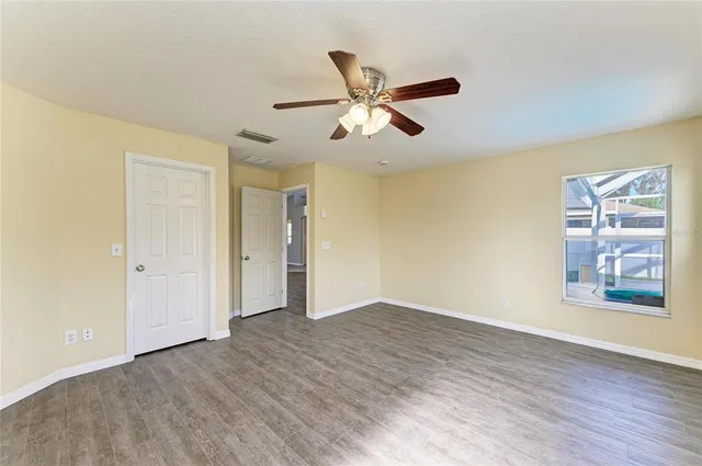 a view of an empty room with window and wooden floor