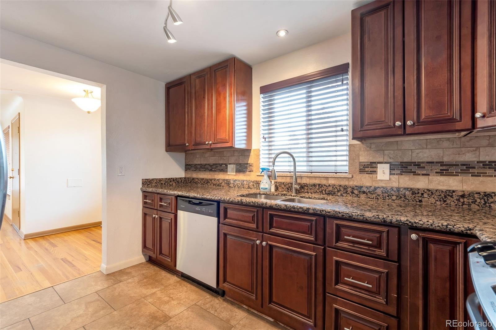 4901 Grove Street Denver, CO 80221 - Photo 5 of 25 a kitchen with stainless steel appliances granite countertop wooden cabinets a sink and dishwasher