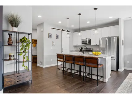 a kitchen with stainless steel appliances kitchen island granite countertop a refrigerator a stove a sink and a dining table with wooden floor