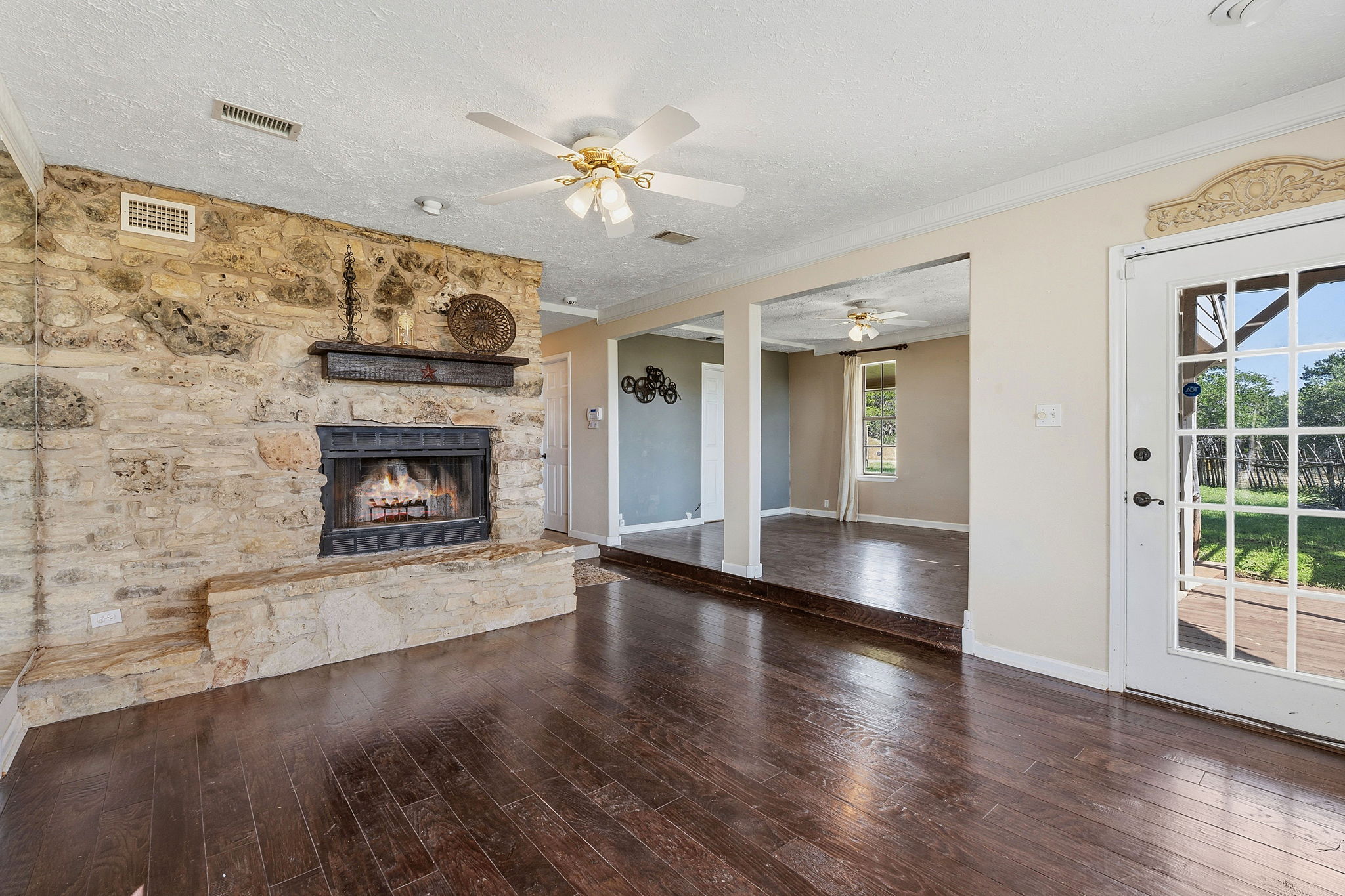 3230 West Fitzhugh Road Dripping Springs, TX 78620 - Photo 9 of 34 A stone fireplace anchors this living space, complementing rich hardwood flooring and a bright glass-paned door.