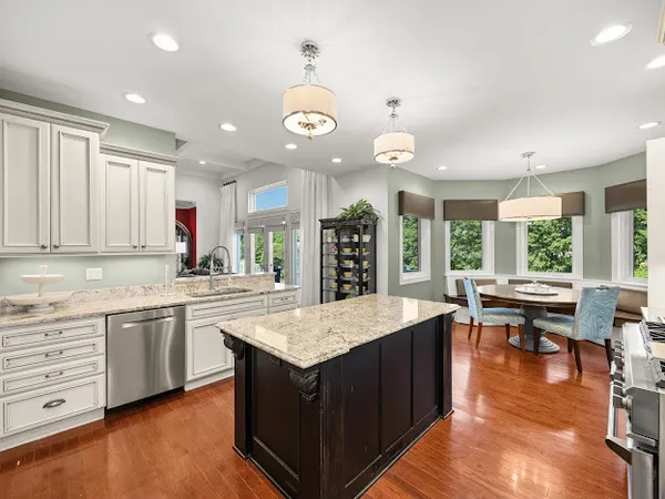 a kitchen with granite countertop a stove a sink a dining table and chairs with wooden floor