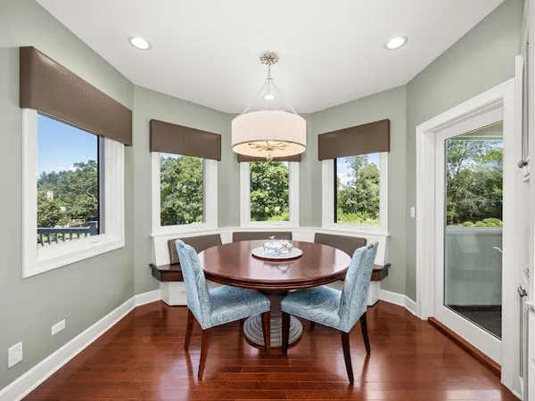a dining room with wooden floor a chandelier a glass table and chairs