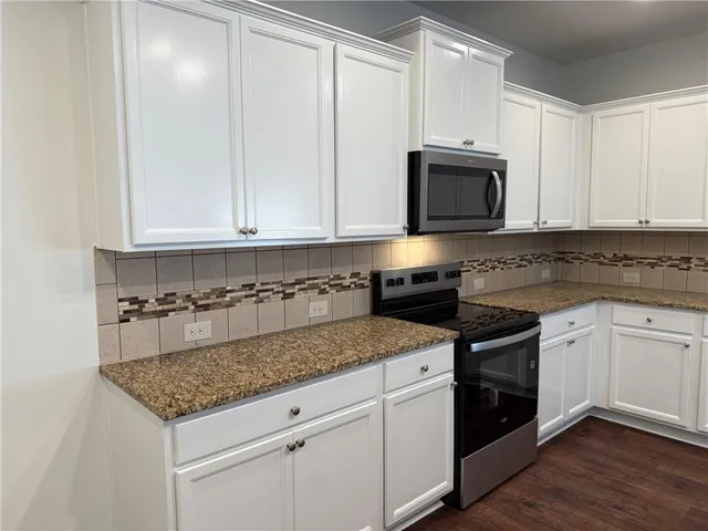 a kitchen with granite countertop a sink stainless steel appliances and white cabinets