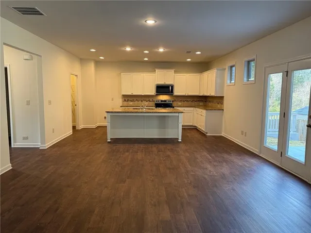 a open kitchen with kitchen island a sink dishwasher stove and white cabinets with wooden floor