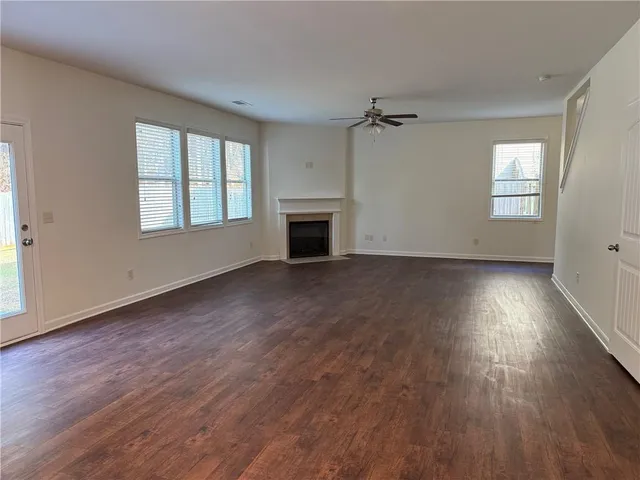 an empty room with wooden floor fireplace and windows