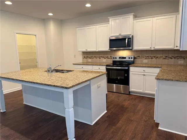 a kitchen with stainless steel appliances granite countertop a stove a sink and a microwave