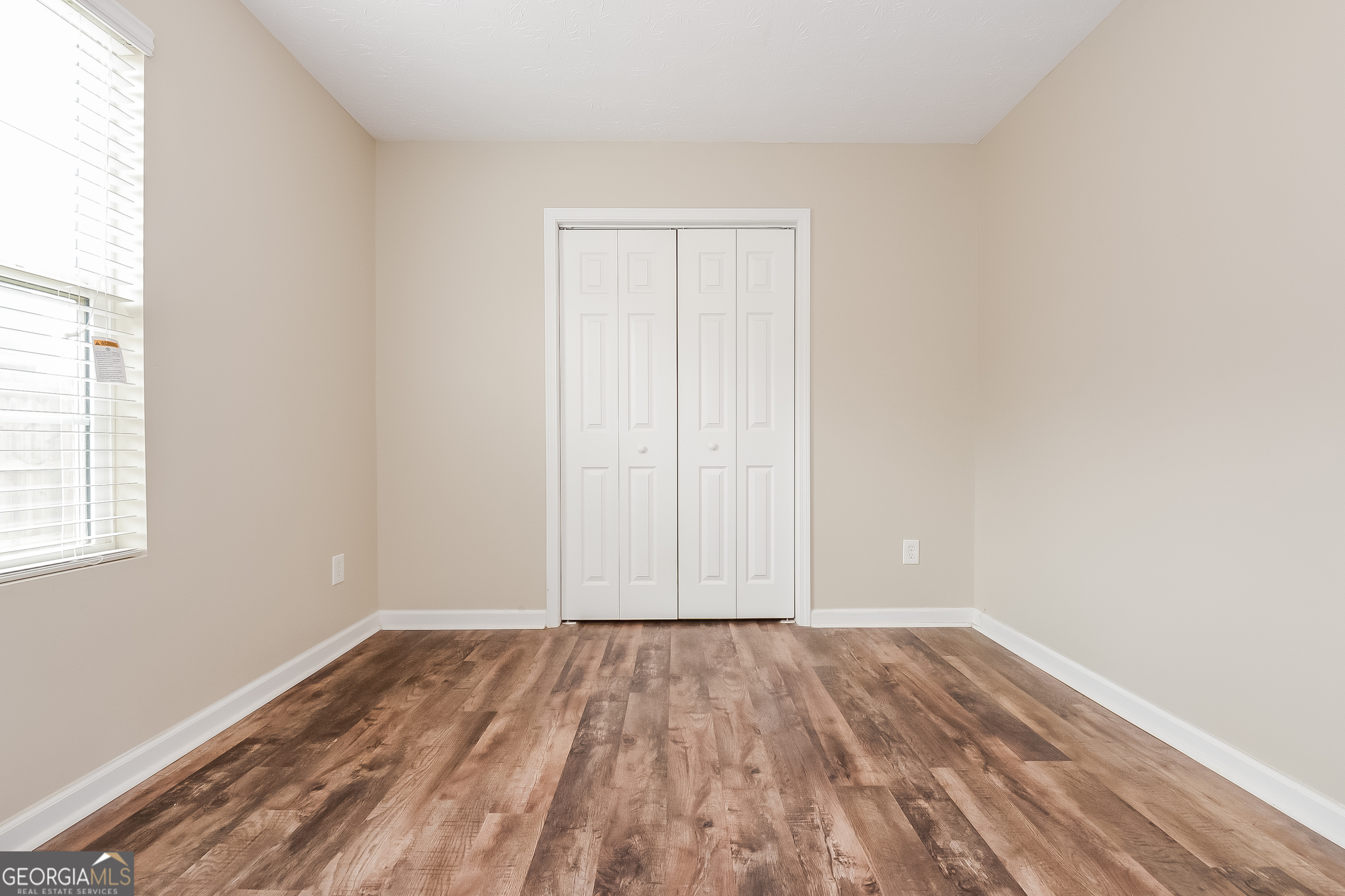 5179 Tew Lane Southwest Covington, GA 30014 - Photo 12 of 16 an empty room with wooden floor and windows