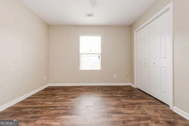 an empty room with wooden floor and windows