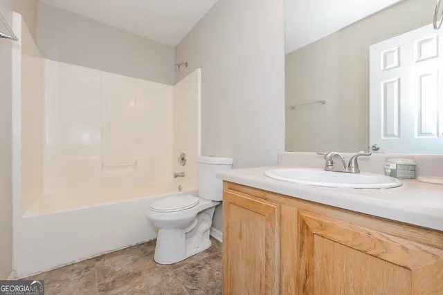 a bathroom with a granite countertop sink a toilet and a mirror