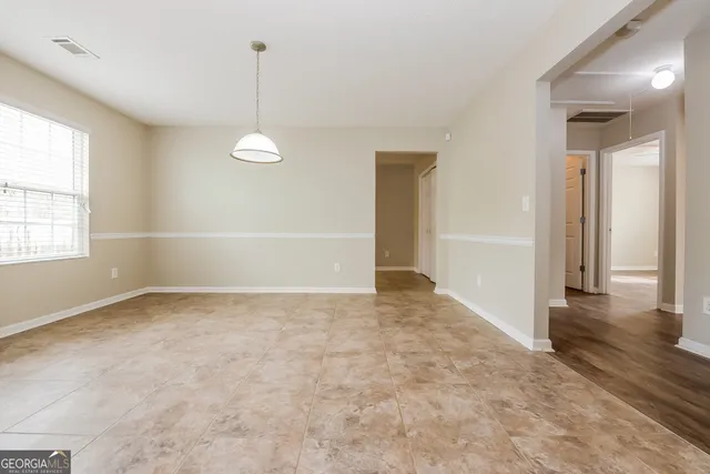 an empty room with windows and ceiling fan