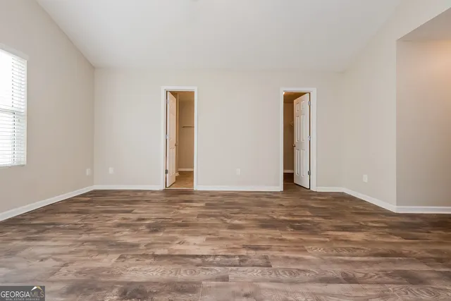 a view of an empty room with window and wooden floor