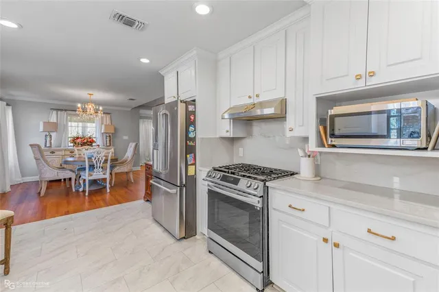 a kitchen with stainless steel appliances granite countertop a stove top oven a sink a dining table and chairs