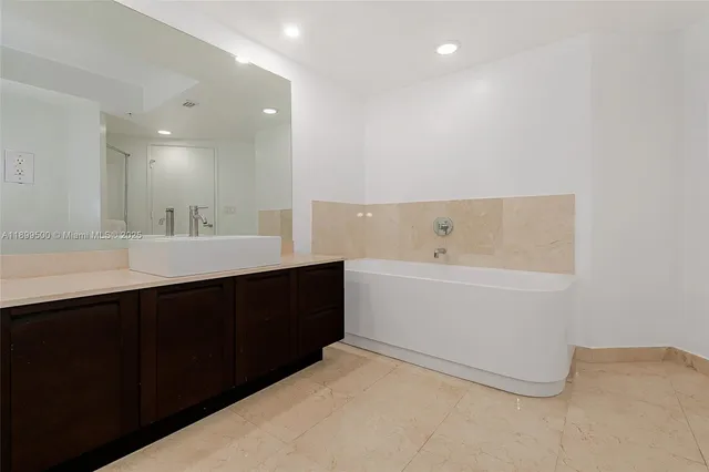 a bathroom with a double vanity sink a mirror and a bathtub