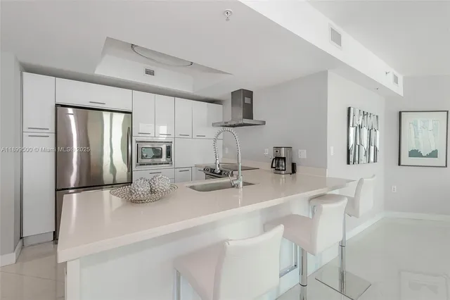 a kitchen with refrigerator and chairs