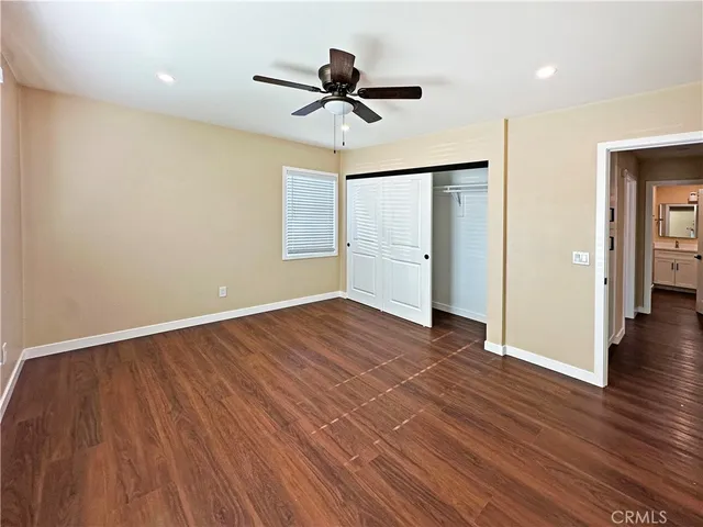 a view of empty room with wooden floor and ceiling fan