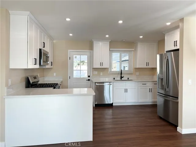 a kitchen with stainless steel appliances granite countertop a refrigerator sink and white cabinets