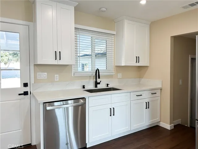 a kitchen with white cabinets and sink