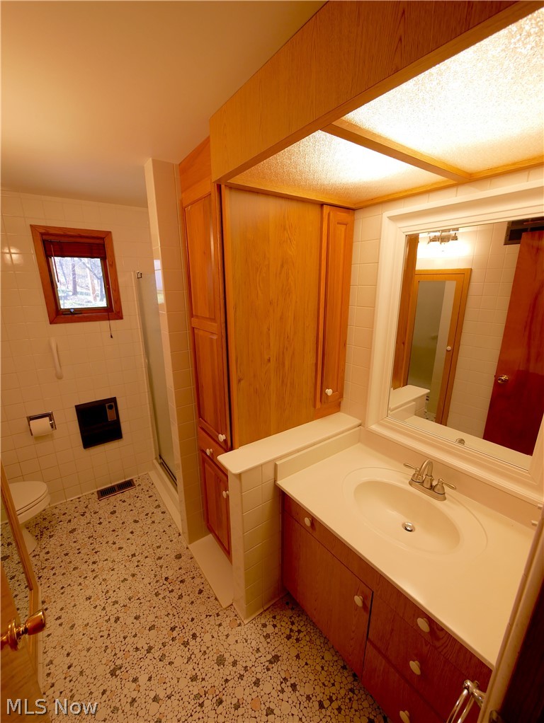 57500 Hospital Road Bellaire, OH 43906 - Photo 15 of 22 Bathroom with toilet, a textured ceiling, vanity with extensive cabinet space, walk in shower, and tile walls